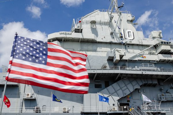 US flag waves in front of the USS Yorktown at Patriots Point